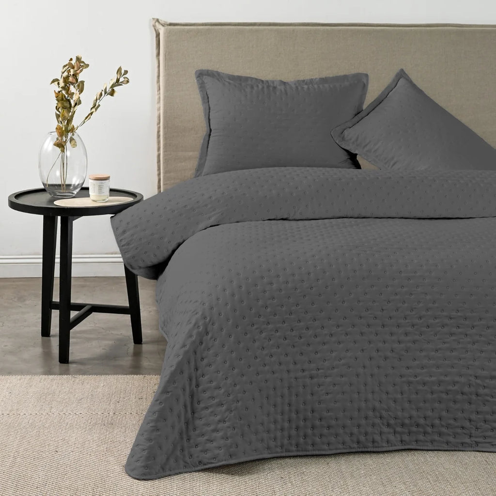 Quilt Drops Gris Oscuro American Family sobre la cama