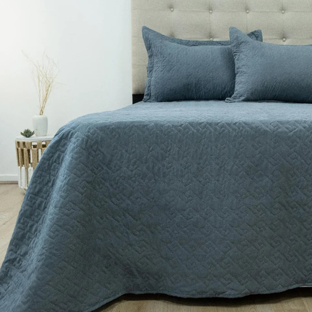 Quilt Velvety azul grisáceo Doral sobre cama, superficie afelpada
