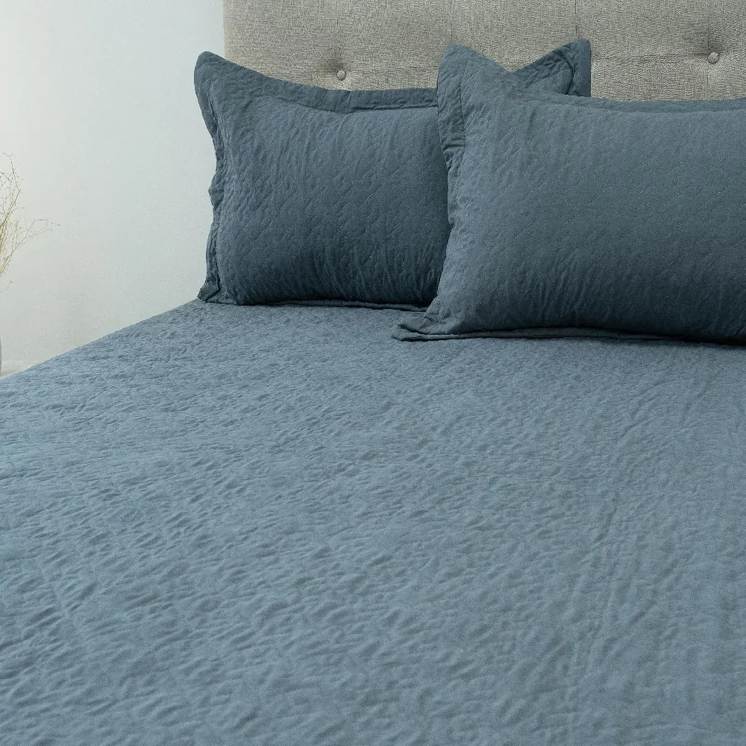 Quilt Velvety azul grisáceo Doral sobre cama, superficie afelpada
