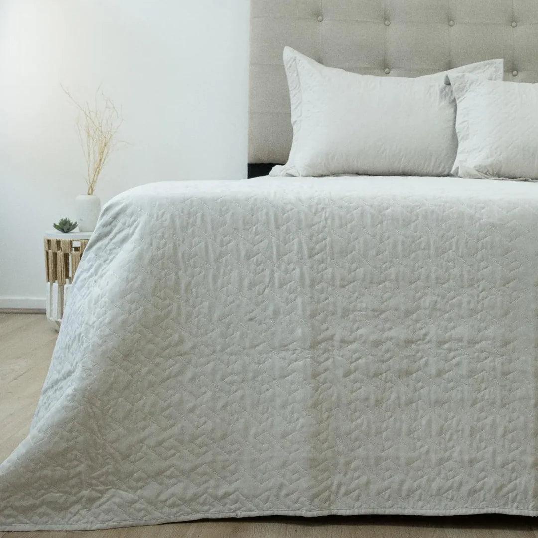 Quilt Velvety beige Doral sobre cama, superficie afelpada