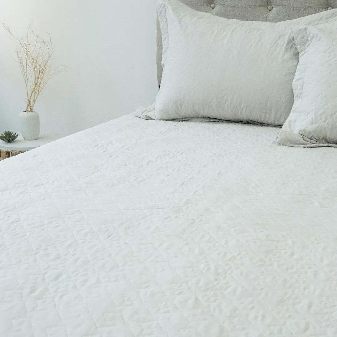 Quilt Velvety beige Doral sobre cama, superficie afelpada