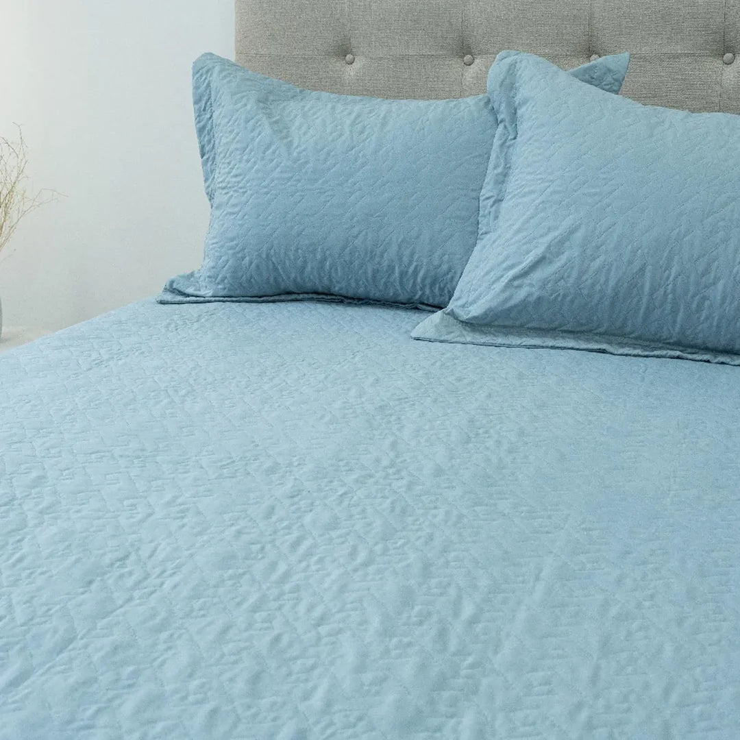 Quilt Velvety celeste Doral sobre cama, superficie afelpada