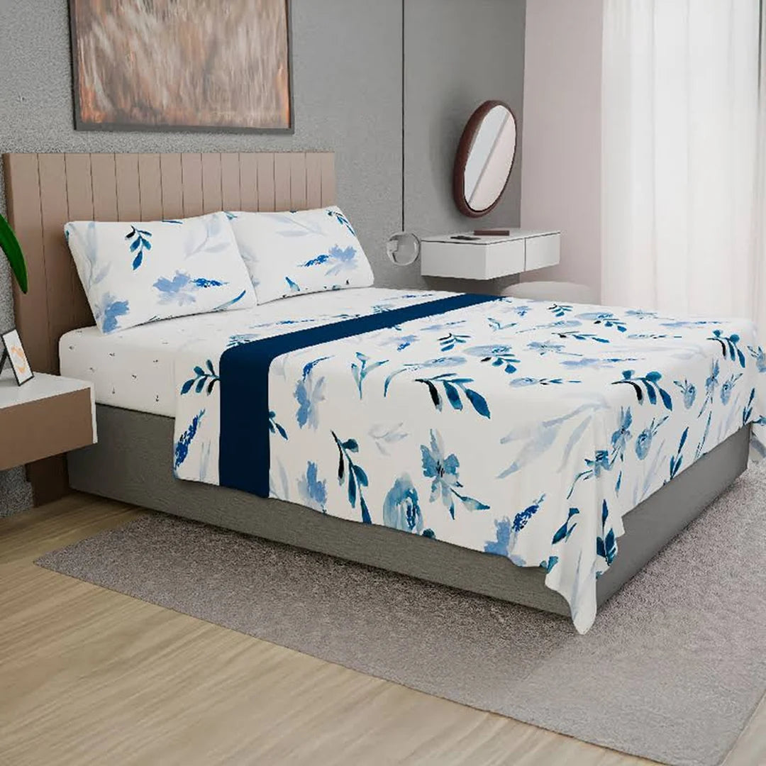 Sábana Acuarela Doral sobre cama, flores azules en acuarela sobre blanco con franja azul marino
