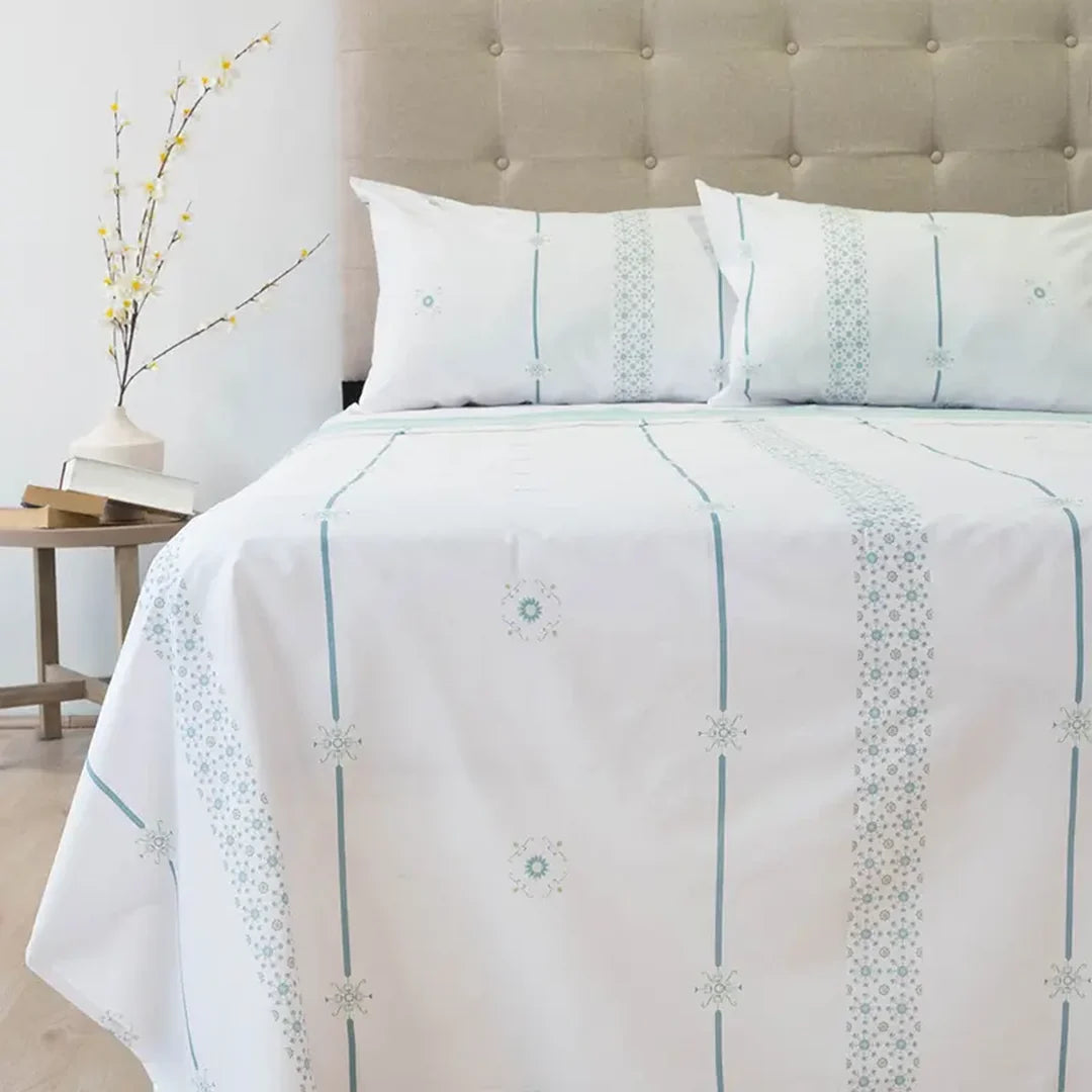 Sábana Guipur Doral sobre cama, franjas de encaje y estrellas en verde agua sobre blanco