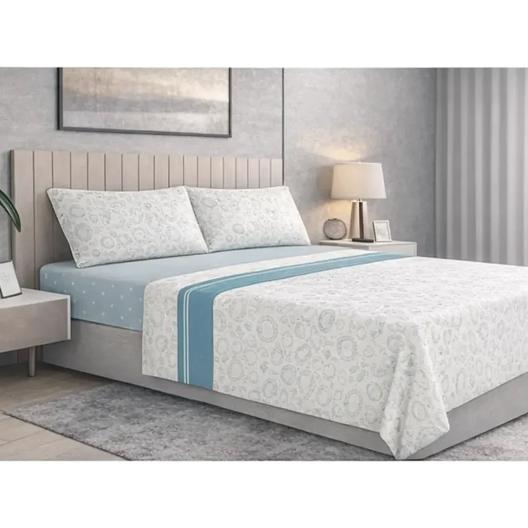 Sábana Nácar Doral sobre cama, formas redondeadas gris claro tono sobre tono con cenefa celeste